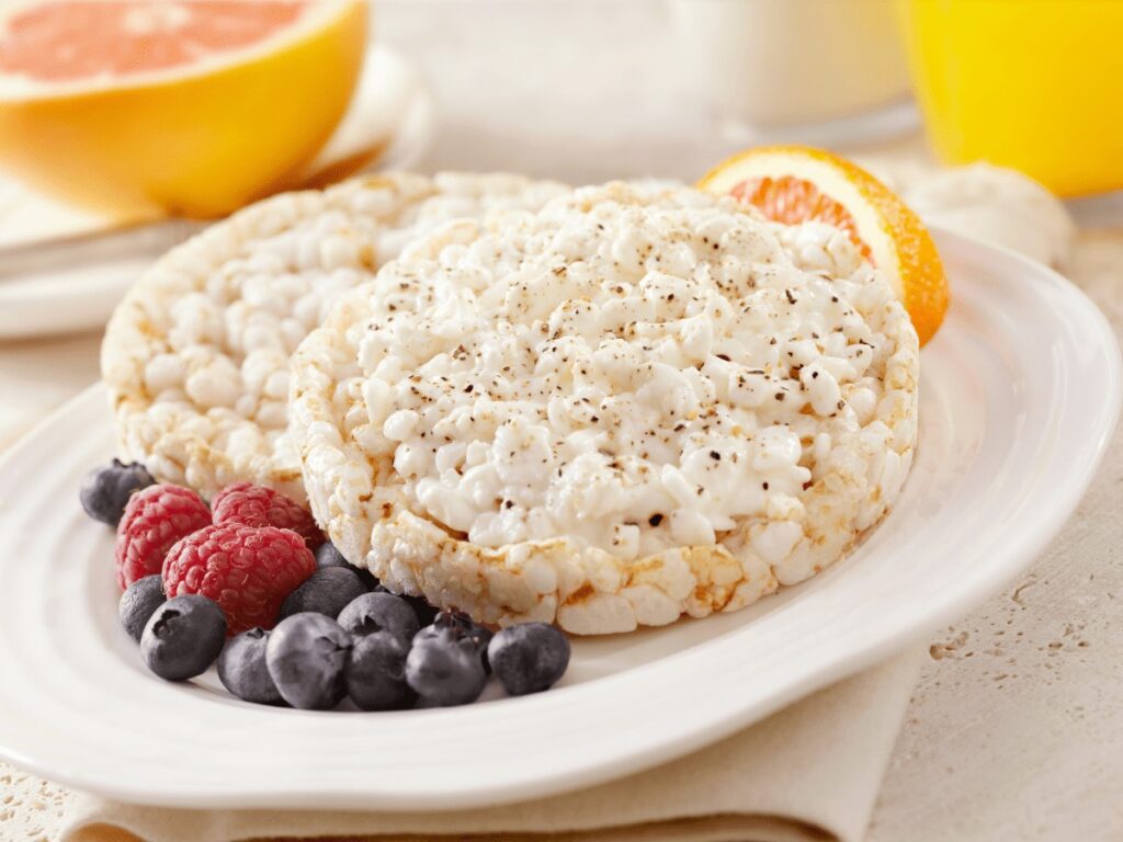 healthy rice cake toppings image of rice cakes in a bowl with berries and an orange slice beside it.