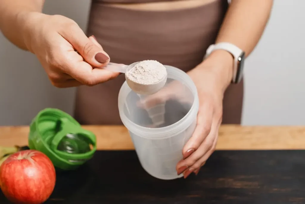 Woman scooping creatine powder supplement in a gym setting