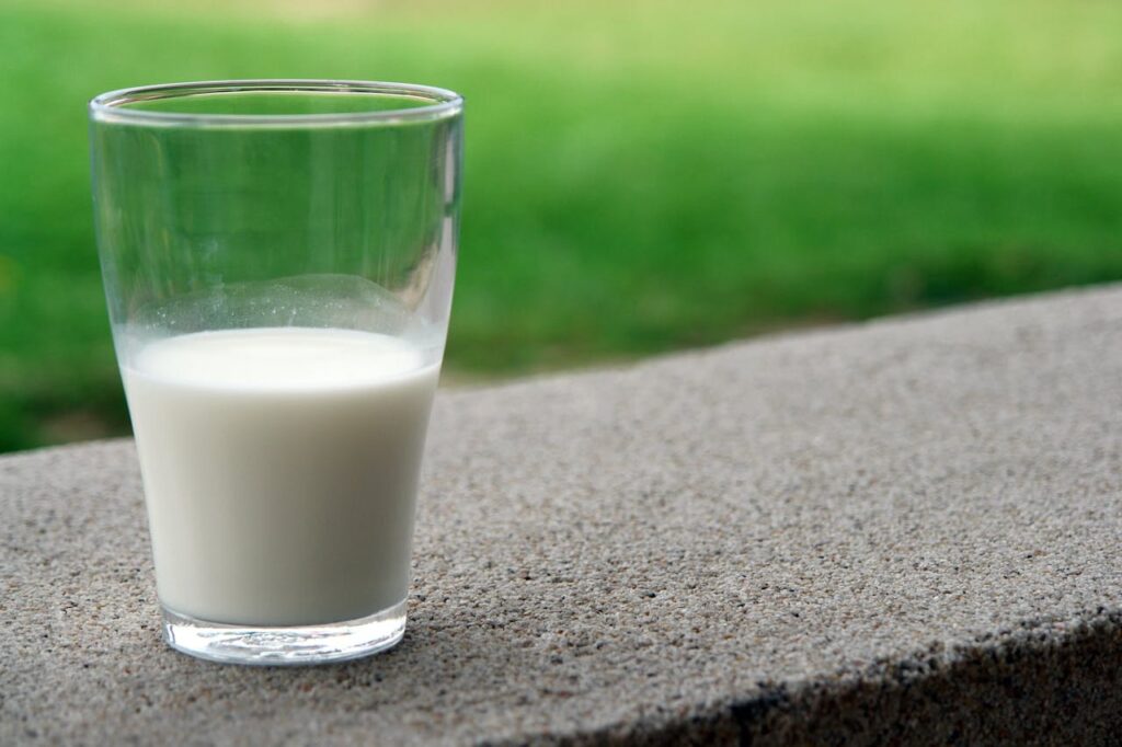 Glass of milk on a ledge representing lactose intolerance vs dairy sensitivity and milk allergy.