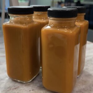 Carrot apple ginger juice shots in glass jars prepared for meal prep