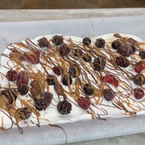 Frozen Greek yogurt berry bark topped with mixed berries, peanut butter, and chocolate.