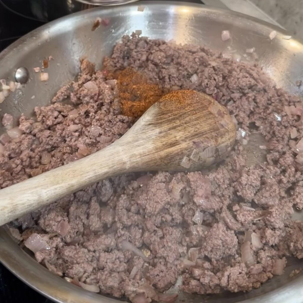 Cooking lean ground beef, onions, and taco seasoning for high protein breakfast burrito filling.