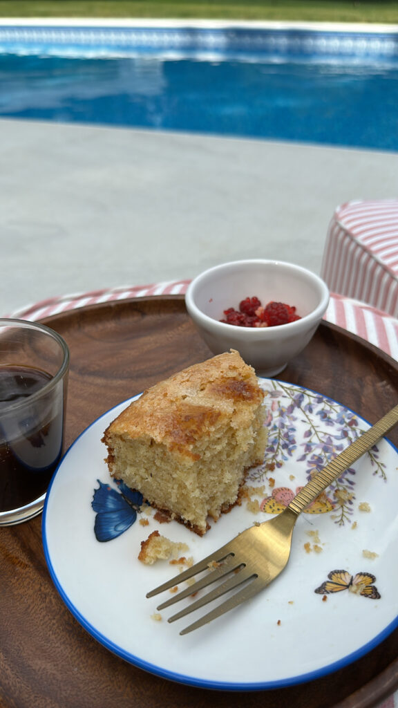 Slice of lemon olive oil cake served with coffee and raspberries by the pool